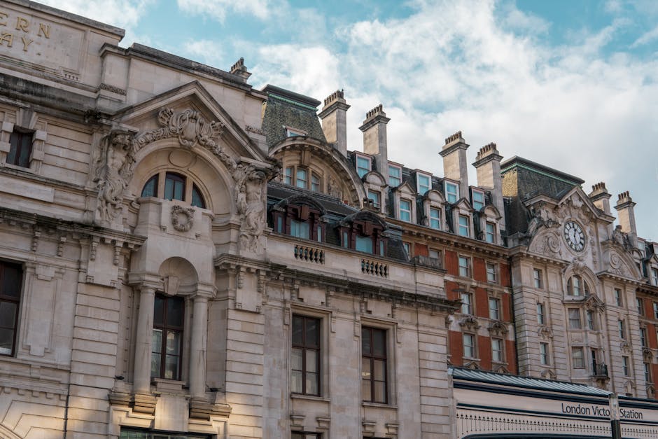 Exterior view of a historic multi-story building near Victoria Station in Westminster, London, featuring ornate architectural details such as decorative stone carvings, arched windows, and a large clock face. The building has a classic facade with cream-colored stonework, numerous chimney stacks on the roof, and dormer windows with dark framing. The sky above is partly cloudy with patches of blue. This image highlights the historic architecture common to Westminster, and is unrelated to cleaning processes or surfaces.
